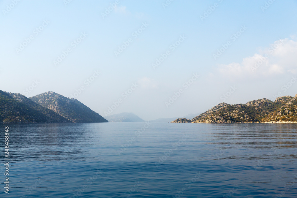 Mediterranean sea overlooking the mountains. Aerial top view of sea waves hitting rocks on the beach with turquoise sea water. Amazing rock cliff seascape in the coastline. Mediterranean sea overlooking the mountains. Aerial top view of sea waves hitting rocks on the beach with turquoise sea water. Amazing rock cliff seascape in the coastline.