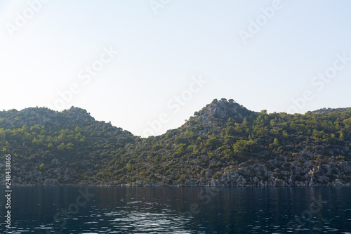 Mediterranean sea overlooking the mountains. Aerial top view of sea waves hitting rocks on the beach with turquoise sea water. Amazing rock cliff seascape in the coastline.