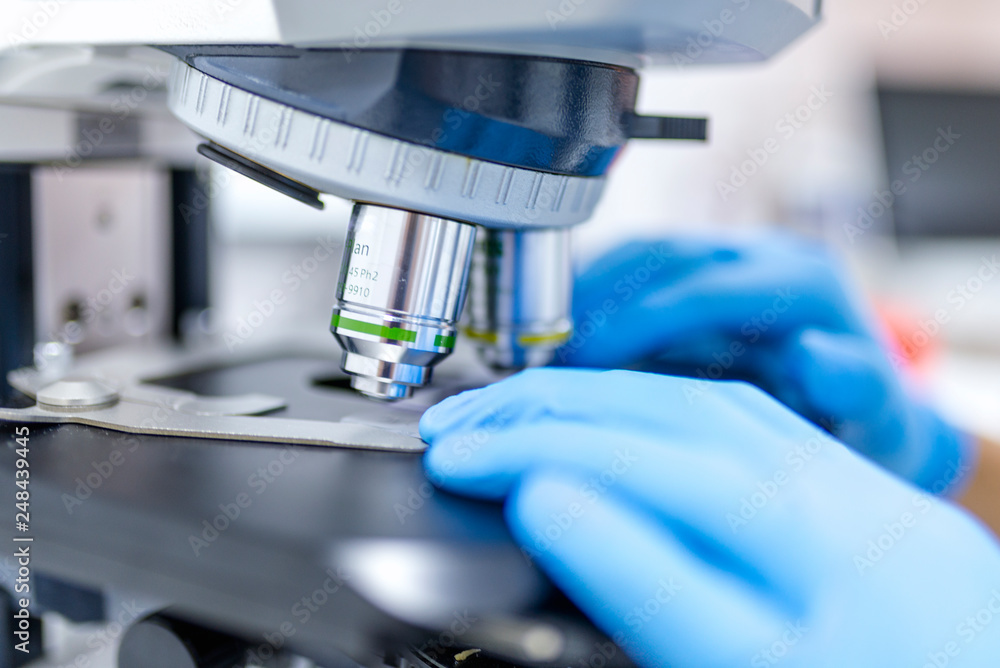 Close-up of scientist hands with microscope, examining samples and liquid Close-up of scientist hands with microscope, examining samples and liquid