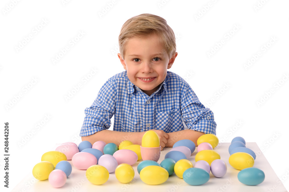 The child is painting eggs for Easter day. Nice, smiling boy sitting at a table with colorful eggs in baskets, yellow chicks. Happy Easter. Isolated on a white.