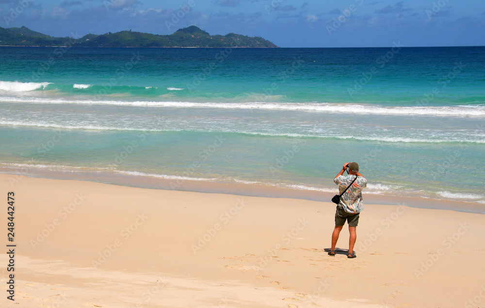 man photographs seascape on a sandy beach