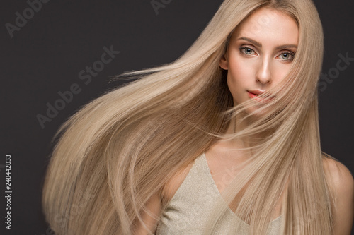 Beautiful blond girl in move with a perfectly smooth hair, and classic make-up. Beauty face.