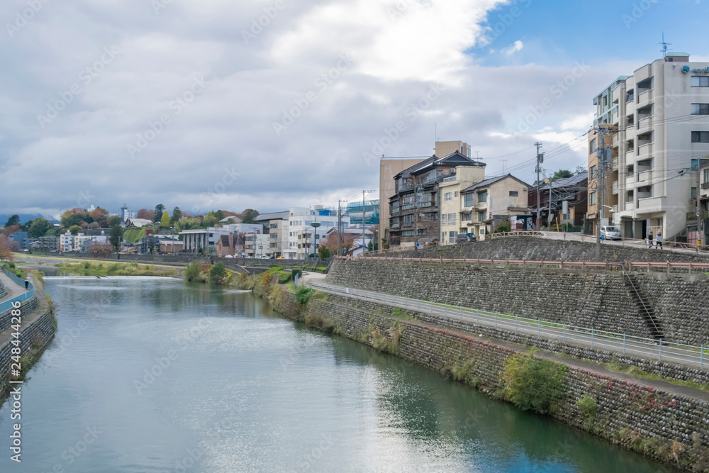Urban or park background featuring Saigawa river and bridges across in residential district of Kanazawa, Japan, in cloudy autumn day in November. 