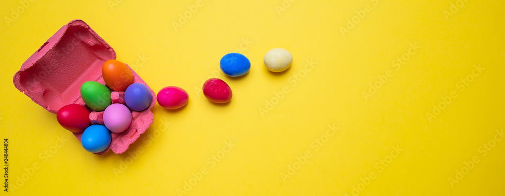 Obraz premium Easter eggs, pastel colors painted and a carton case, yellow background, banner
