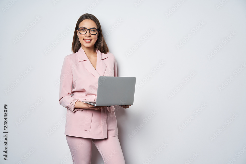 Confident business woman wearing pink suit holding opened laptop