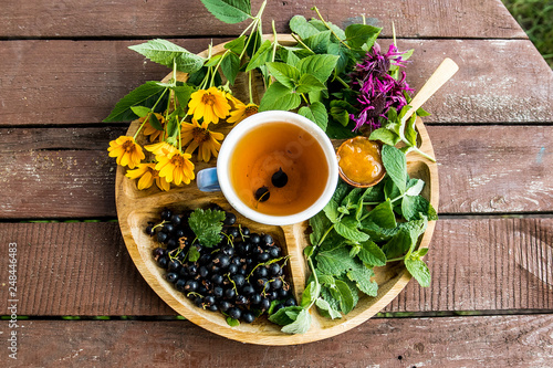 Fotografija tea on a tray on a table above the berries ššta mint echinacea camomile jam apri