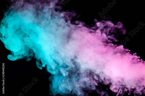 Translucent, thick smoke, illuminated by light against a dark background, divided into three colors: blue, green and purple, burns out, evaporating from a steam of vape.