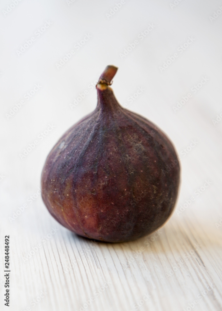 Fresh fig on a white wooden background, side view. Closeup. Fresh fig on a white wooden background, side view. Closeup.