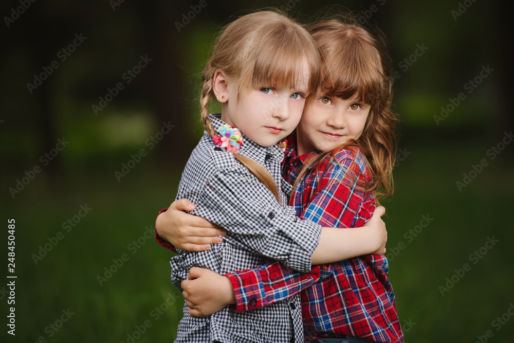 two girls hugging each other on green two girls hugging each other on green