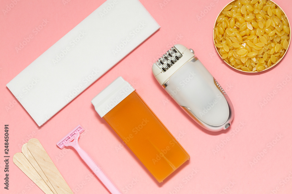 Obraz premium Beauty, depilation and hair removal concept - wax, spatula, epilator and safety razor on pink background. Top view.
