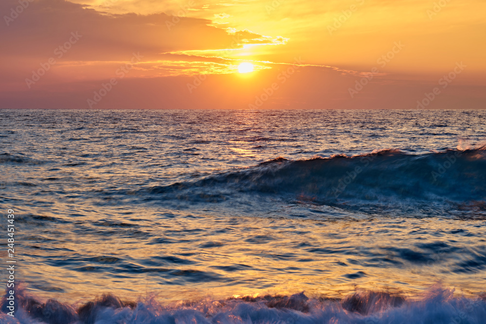 Tropical beach. Colorful sunset seascape. Waves with foam hitting sand.