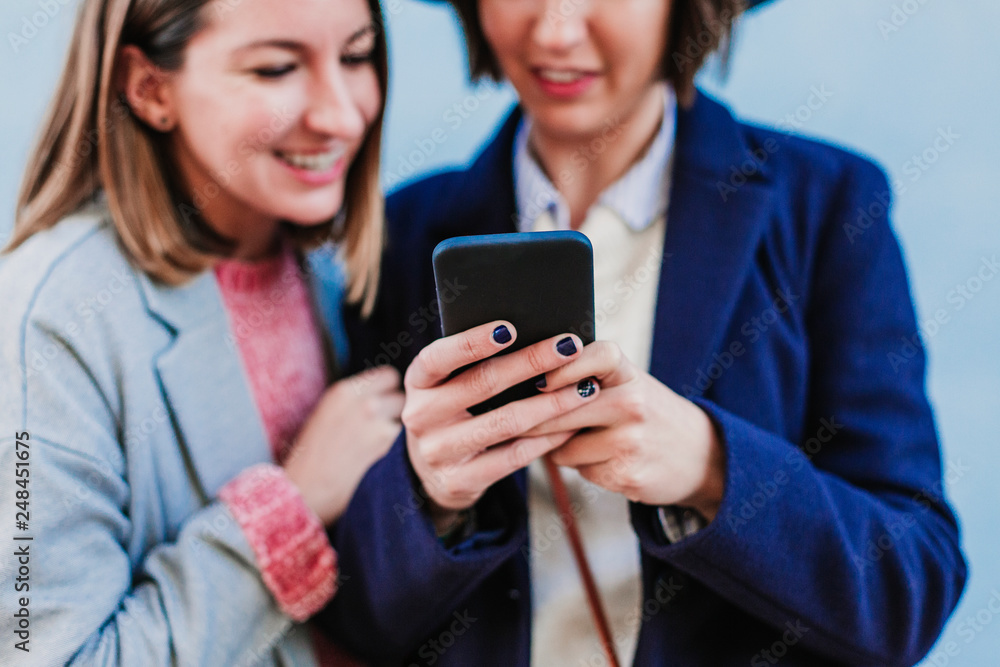 two friends outdoors with stylish clothes taking a selfie with mobile phone. lifestyle two friends outdoors with stylish clothes taking a selfie with mobile phone. lifestyle