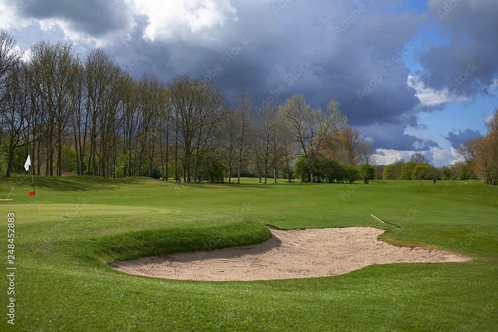 Landscape of a beautiful golf course with greens and holes and bunkers Landscape of a beautiful golf course with greens and holes and bunkers