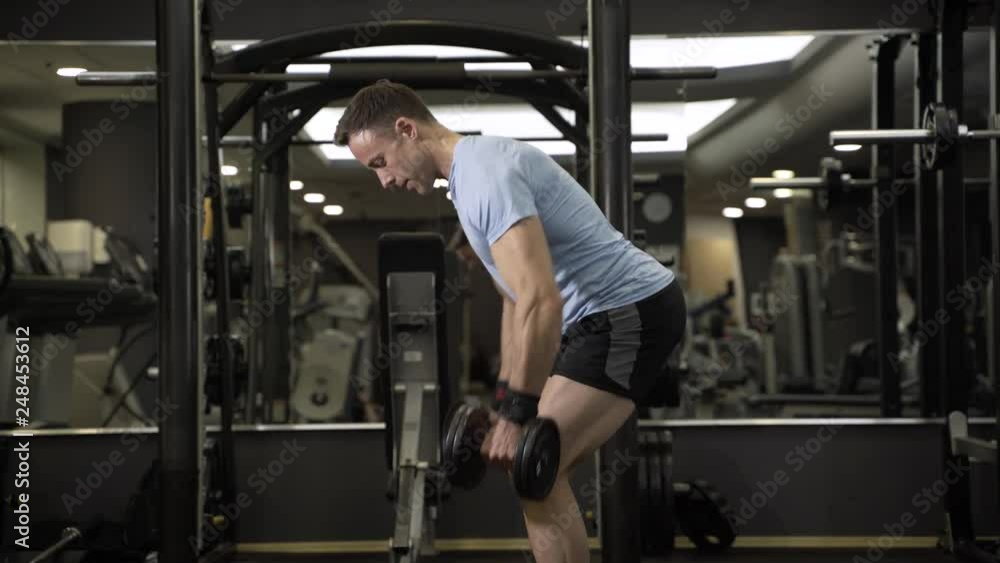 Muscular man pulling heavy dumbbell at the gym. Muscular man pulling heavy dumbbell at the gym.