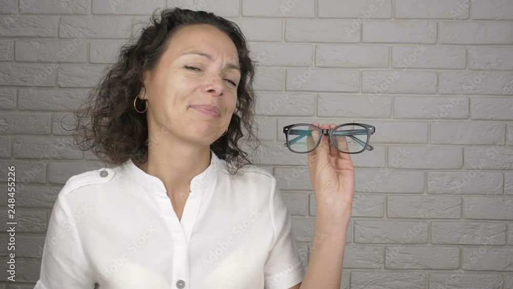 Woman looking for rim for the glasses. Happy woman holds glasses for vision in her hands. Woman looking for rim for the glasses. Happy woman holds glasses for vision in her hands.