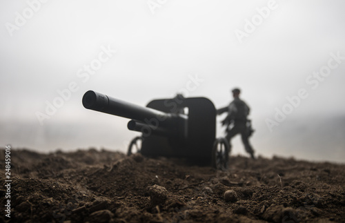 Battle scene. Silhouette of old field gun standing at field ready to fire. With colorful dark foggy background. Selective focus