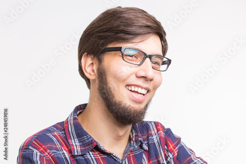 Emotions and people concept - young man in checkered shirt and glasses with beard laughing