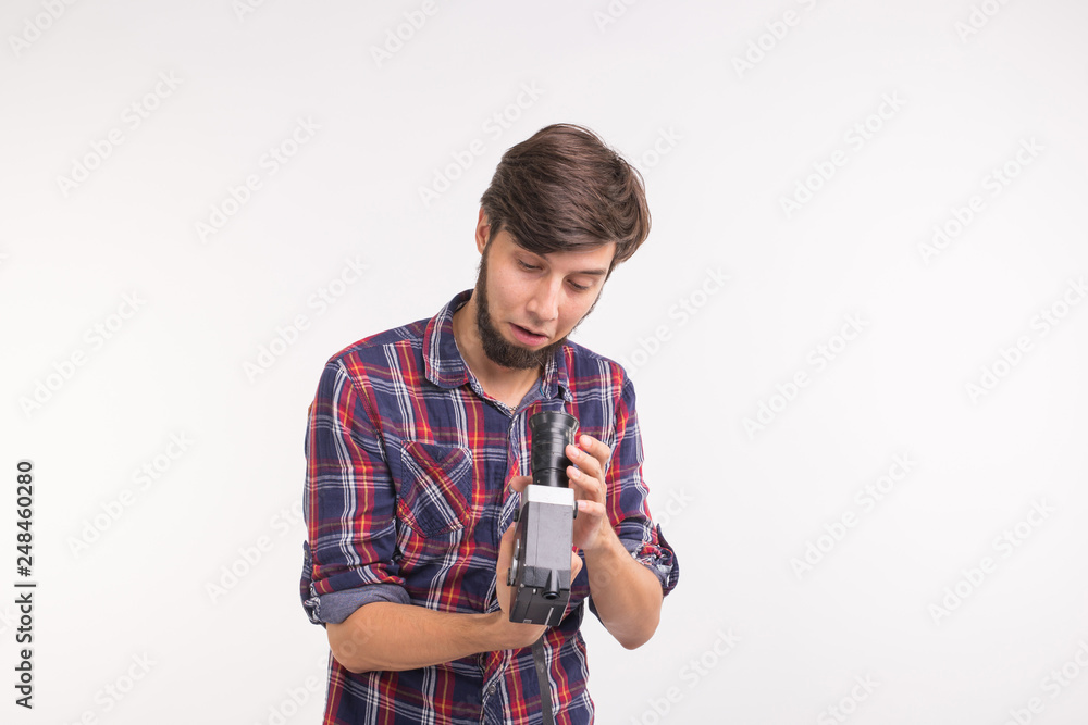 Emotions, photographer and people concept - man look at retro camera and confused because of it Emotions, photographer and people concept - man look at retro camera and confused because of it