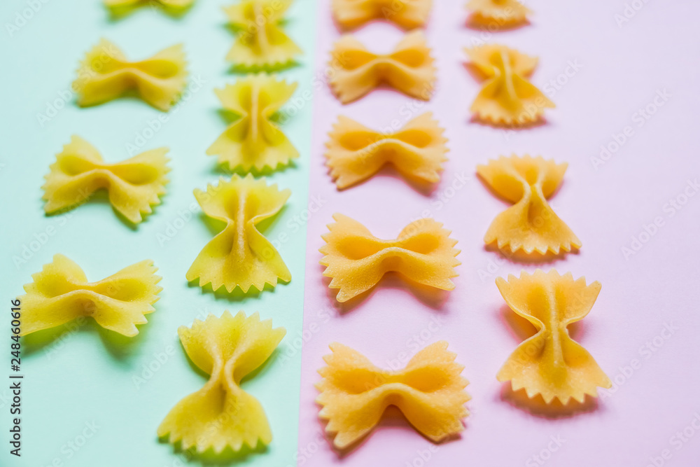 Bow tie Italian pasta fartalle pattern isolated on colorful background, top view. Dry uncooked macaroni concept. Pasta poster. Farfalle Pasta on pink pastel and mint background flat lay. Pattern Bow tie Italian pasta fartalle pattern isolated on colorful background, top view. Dry uncooked macaroni concept. Pasta poster. Farfalle Pasta on pink pastel and mint background flat lay. Pattern