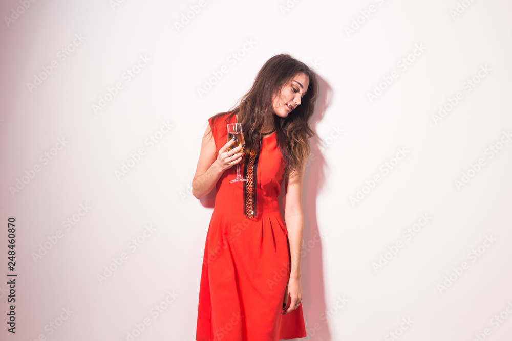 Fototapeta premium Portrait of a beautiful celebrating woman. Holiday lifestyle on white background. Female model in red dress with glass of wine.