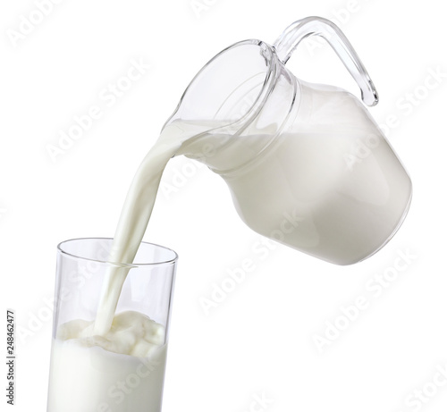 Pouring milk from jug into glass isolated on white background