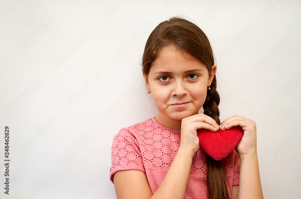 girl on a light background with a red plush heart in her hands girl on a light background with a red plush heart in her hands