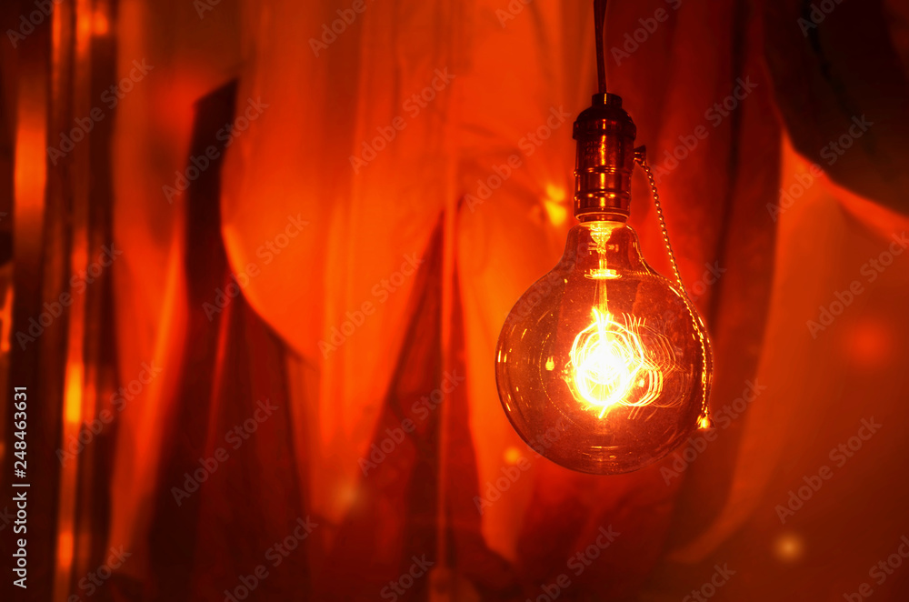 Glowing light bulb on a background of red curtains. Image Glowing light bulb on a background of red curtains. Image