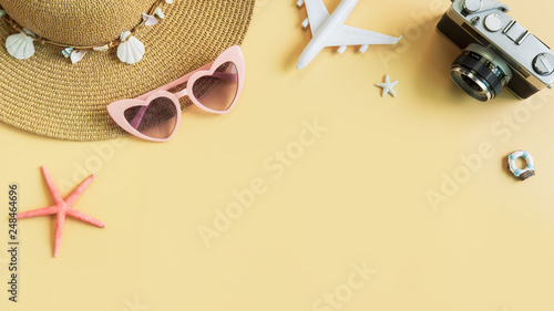 Beach hat with camera and travel items on yellow background, Summer vacation concept