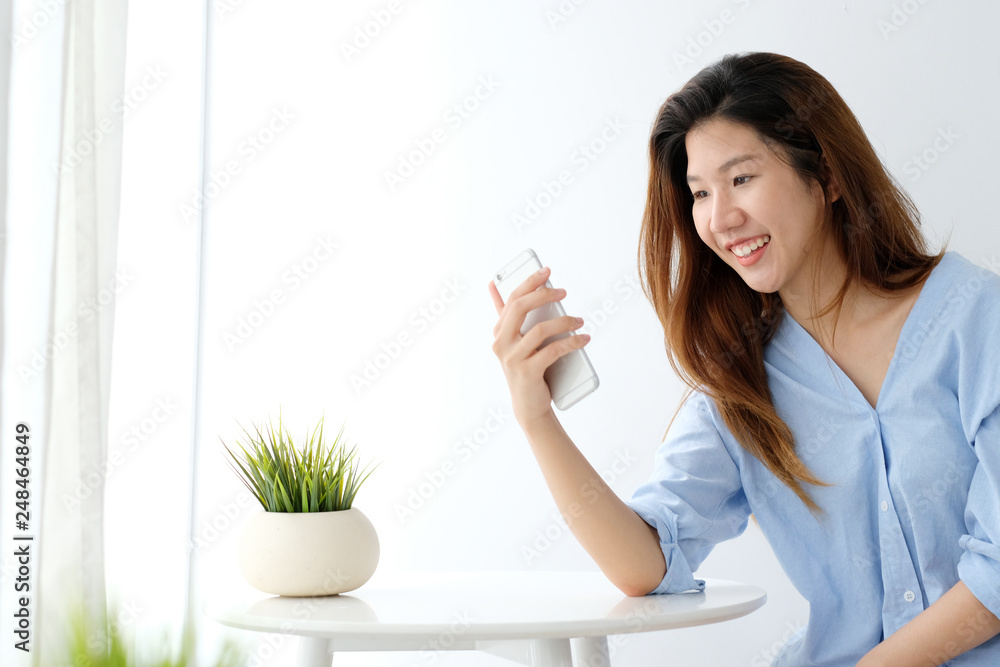 Young asian woman using smart phone with smiling, happy and relax emotion in white room background, people on phone, lifestyle Young asian woman using smart phone with smiling, happy and relax emotion in white room background, people on phone, lifestyle