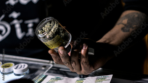 A Vendor Showing Off A Jar Of Cannabis Flowers photo