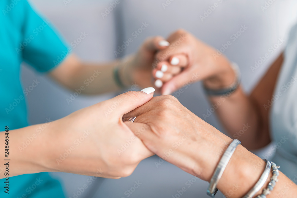 Fototapeta premium Old and young holding hands on light background, closeup