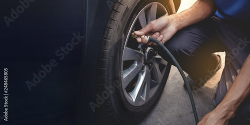 Man filling Air into the Tire. Car Driver Checking Air Pressure and Maintenance his Car by himself before Traveling