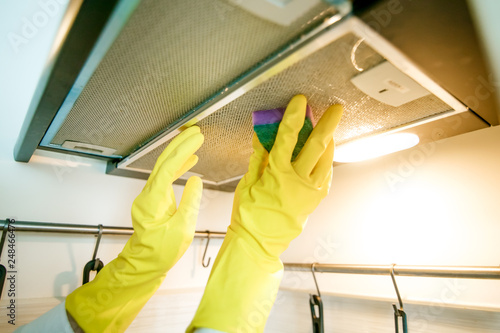 Cleaning the kitchen hood in gloves with detergents. Concept photo for advertising cleaning products and clearing companies.