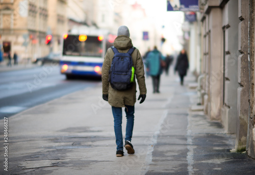 Young student walking down the street with a backpack, in the middle of the roadway. Back to school concept photo, back view, horizontal - Image