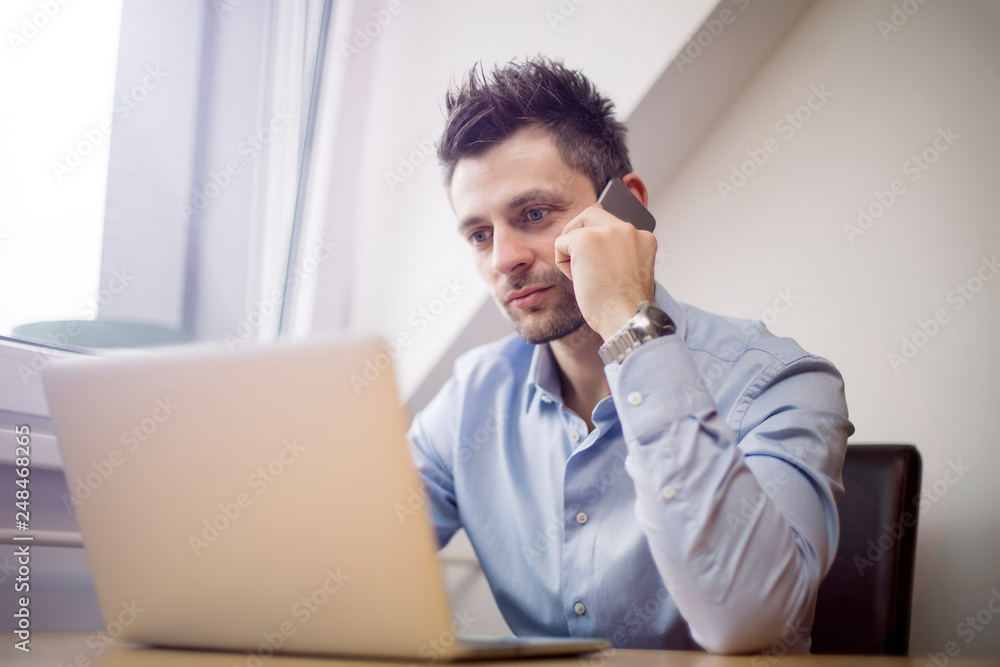 Young businessman using mobile phone and working on laptop Young businessman using mobile phone and working on laptop