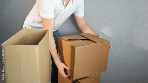 Young delivery service man carrying Boxes Into New Home On Moving Day, copy space
