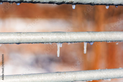 Small ice icicles on the metal railing of the bridge