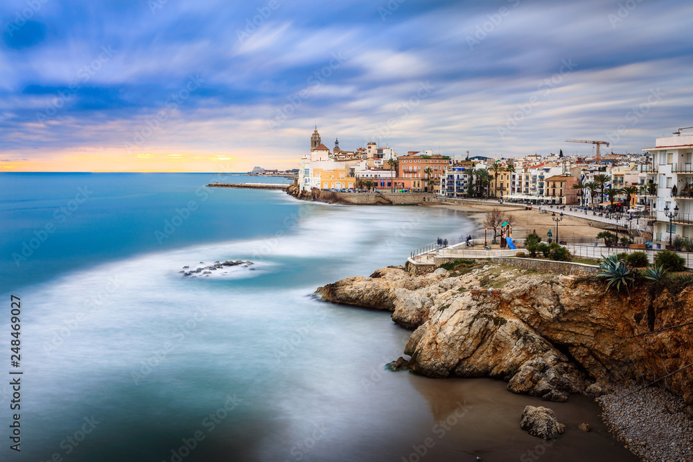 Sitges is known for its beaches, nightspots, and historical sites. The beach seen here is playa san sebastian and the church is a real landmark, san bartolome iglesia.