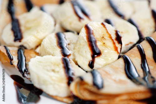Thin delicious pancake with banana and chocolate on white
