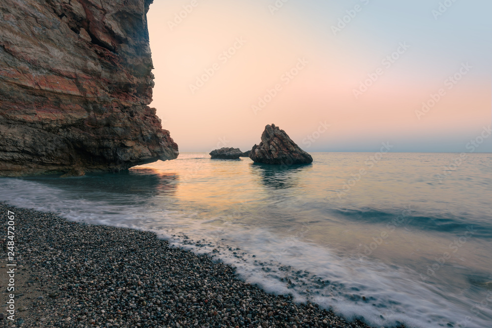 Beautiful sea pebble beach with rocks. Coastal landscape of rocky beach.
