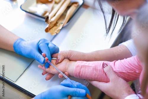 The doctor takes blood tests from the finger of the child with the mother