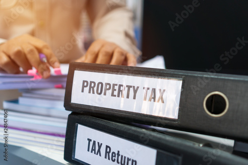 Tax return and property tax folders stack with label black binder on paperwork documents summary report in busy offices by manager checking. HR-human resources business bookkeeping accountancy Concept