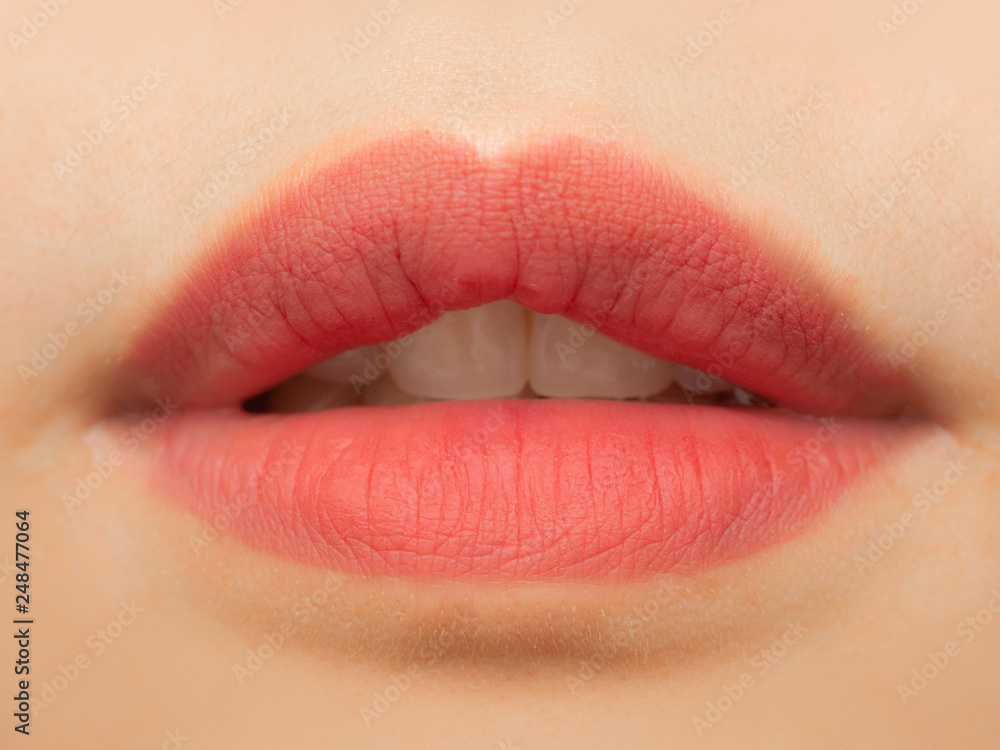 Fototapeta premium Close up view of beautiful woman lips with pink matt lipstick. Open mouth with white teeth. Cosmetology, drugstore or fashion makeup concept. Beauty studio shot. Passionate kiss