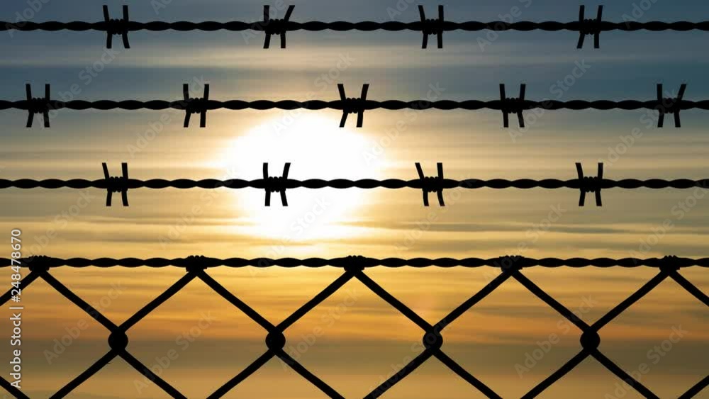 Wired Fence with Barbed Wire and Mesh Steel Wall with Sunset in Background, Concept of Prison, Salvation, Refugee, Lonely Wired Fence with Barbed Wire and Mesh Steel Wall with Sunset in Background, Concept of Prison, Salvation, Refugee, Lonely