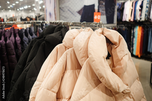 Rack with trendy warm coats of different colors in clothes shop