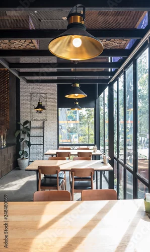Fototapeta na wymiar Table and chair set in modern cafe minimalistic interior design with big window and hanging ceiling lamps