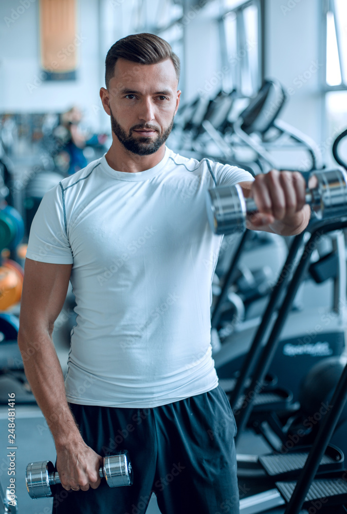 close up.an attractive man works with dumbbells in the gym close up.an attractive man works with dumbbells in the gym