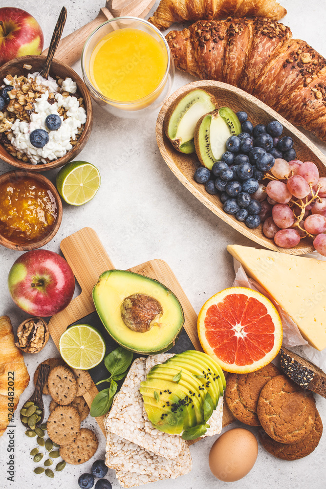 Healthy balanced breakfast on white background. Muesli, juice, croissants, cheese, biscuits and fruit, top view. Healthy balanced breakfast on white background. Muesli, juice, croissants, cheese, biscuits and fruit, top view.