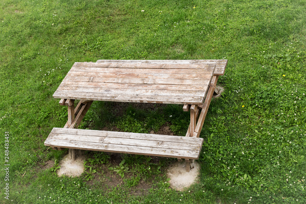 wooden table with benches for picnic in the shade on green lawn