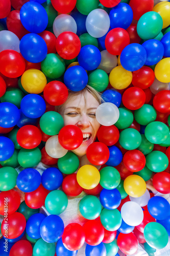 Young blonde girl surrounded with colorful balloons.